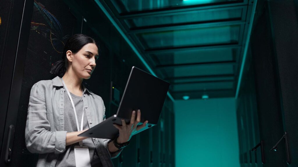 Woman holding a laptop in her hands in a dark room